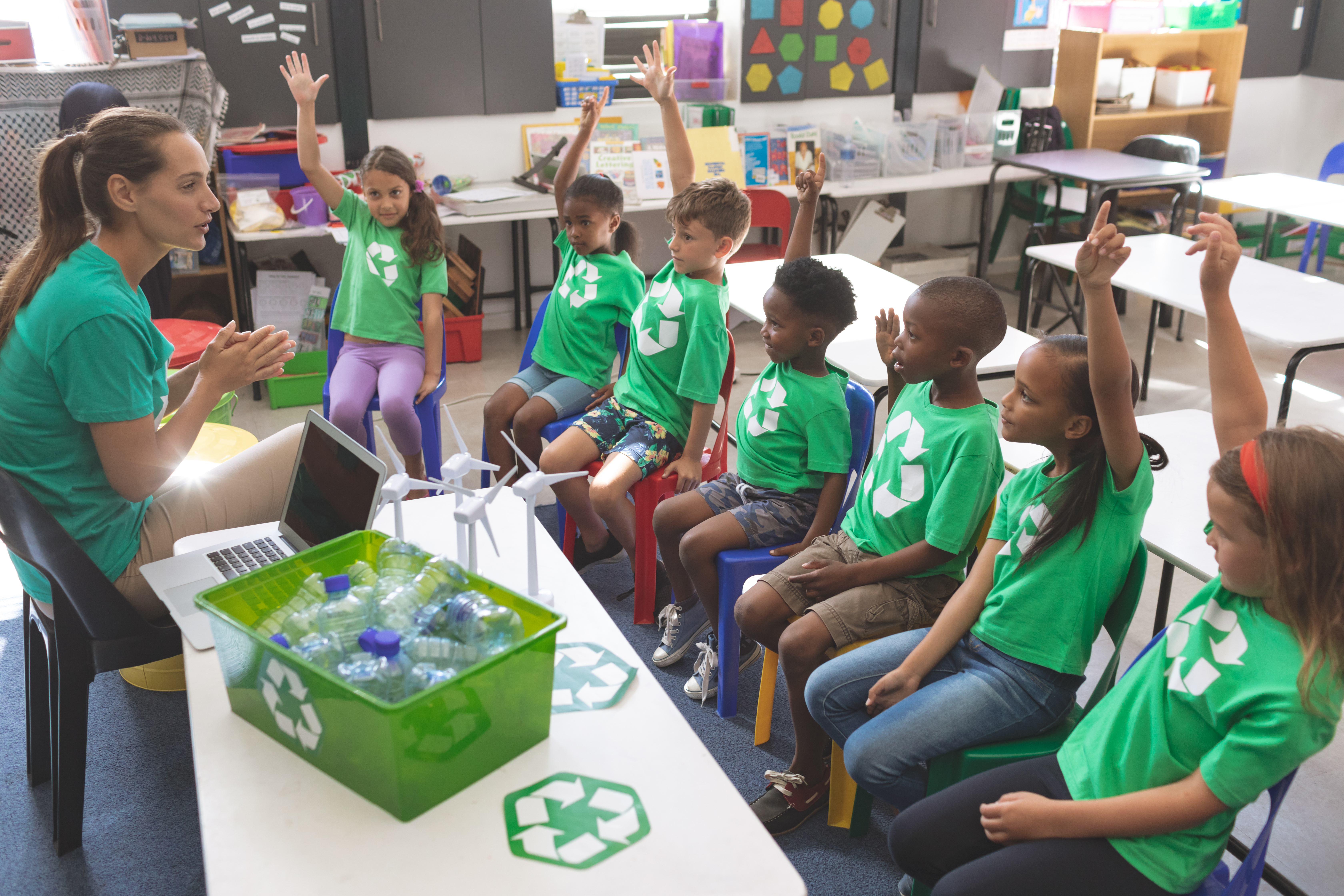 Group of children in classroom wearing green tshirt with recycle symbol on