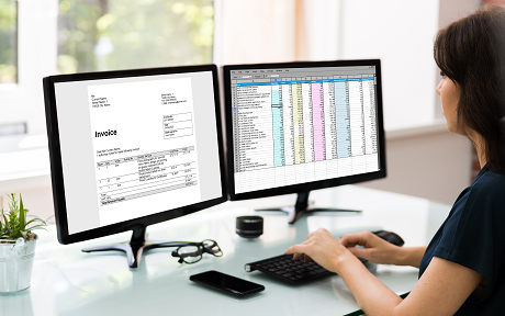 Female office worker sitting at desk looking at spreadsheets on a computer screen 